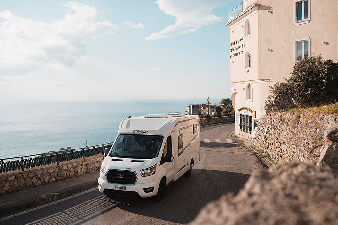 Wohnmobil auf Straße eines mediterranen Küstendorfs