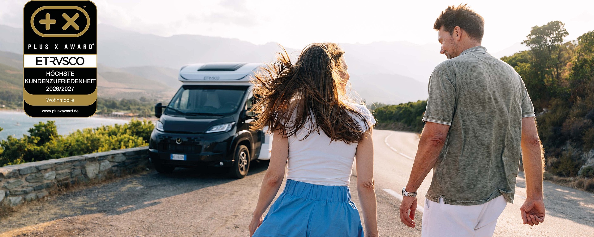 Ein Pärchen geht auf ein schwarzes Etrusco Wohnmobil zu