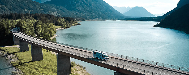 Weißes Reisemobil auf einer Brücke über dem Meer