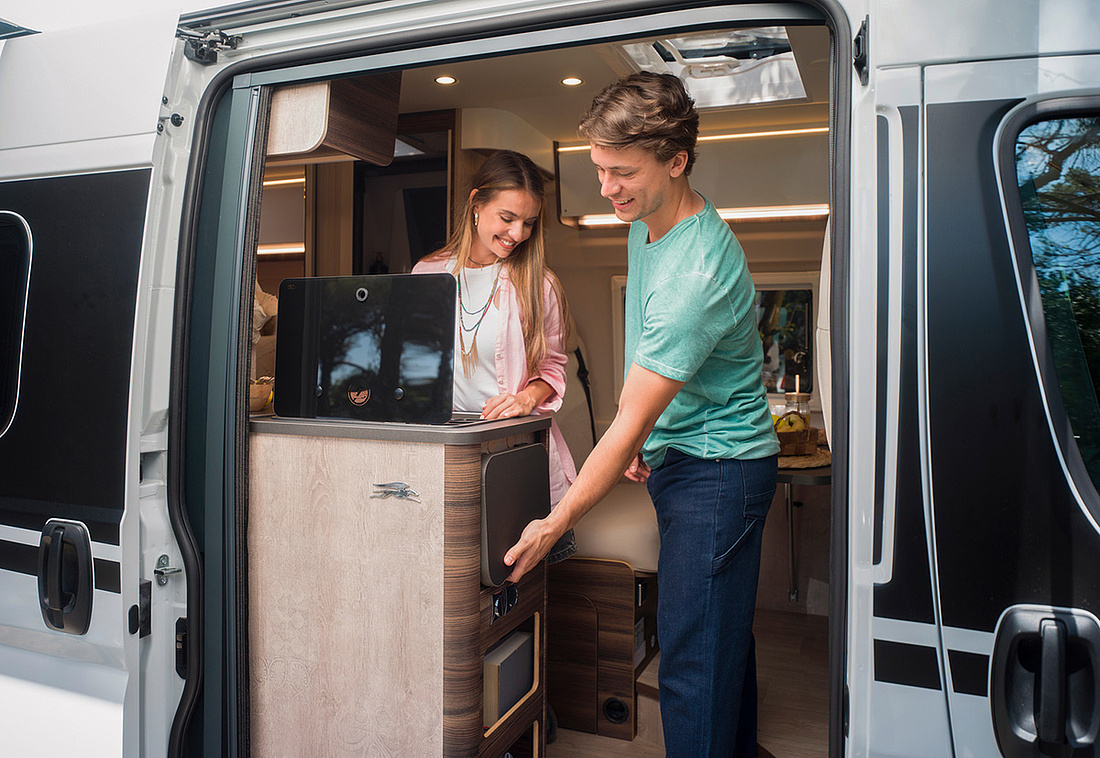 Pärchen im Wohnmobil schauen heraus durch offene Seitentür