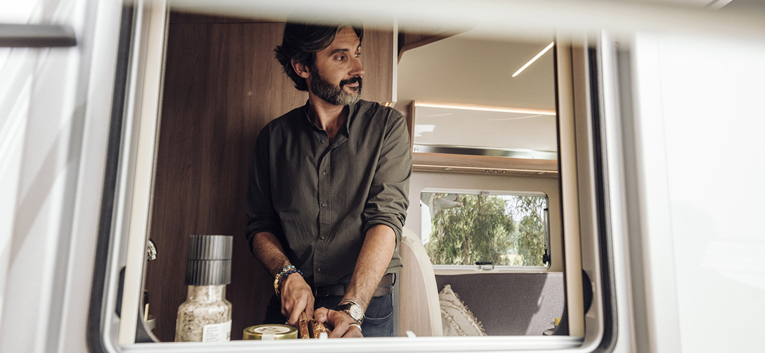 Blick ins Reisemobil Mann bereitet Essen zu