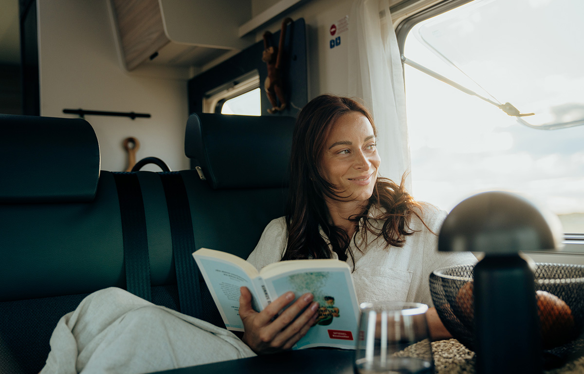 Eine Frau liest im Innenraum eines Reisemobils