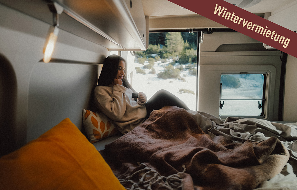 Frau liegt auf Decken im Camper Van